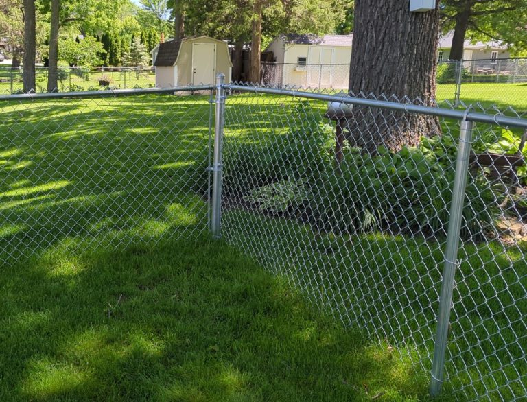 Galvanized chain link fence installation in a residential backyard with green lawn and trees in Cedar Falls, Iowa